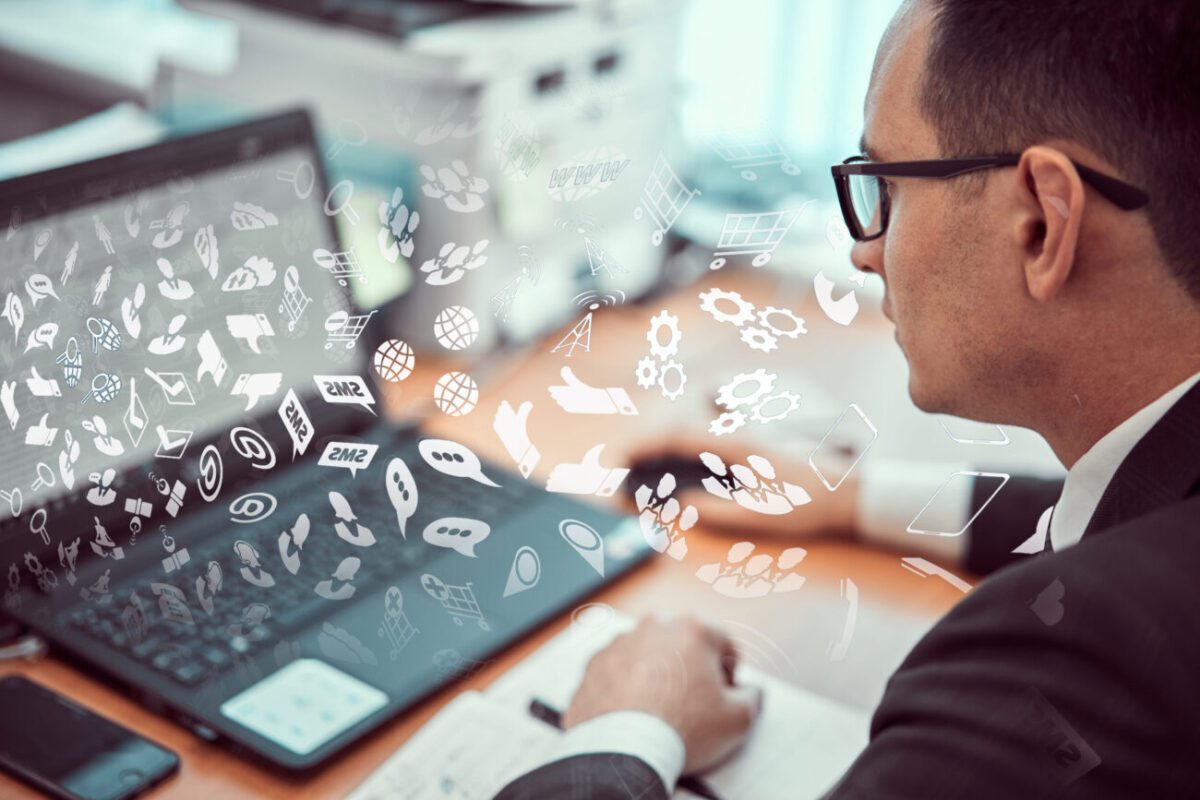 783820 Javier Cortijo Moreno | 49k Noticias Professional man wearing glasses working at a laptop with floating icons and diagrams around the screen, symbolizing digital communication.